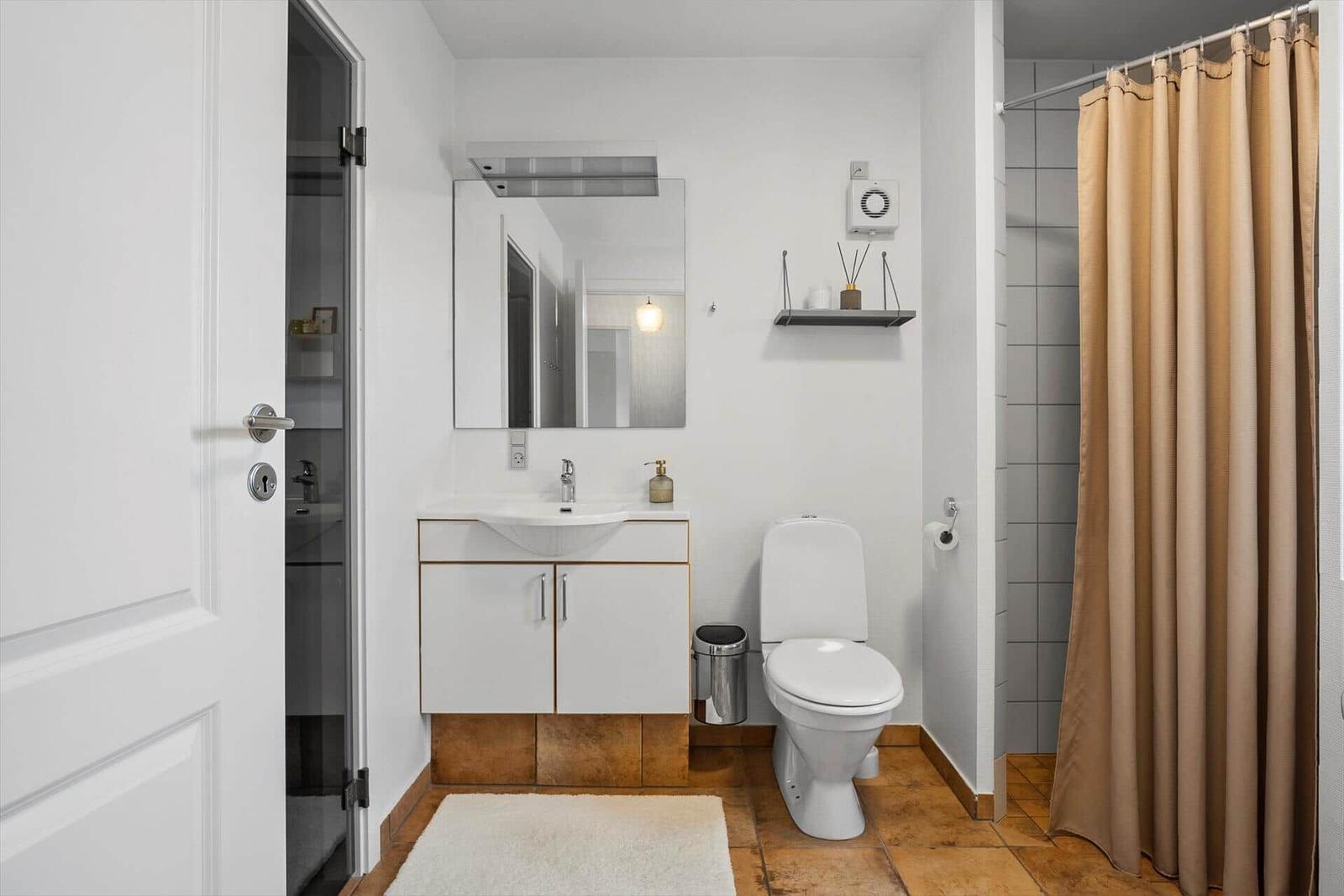 Badezimmer mit Waschbecken, Toilette und Dusche mit Vorhang.