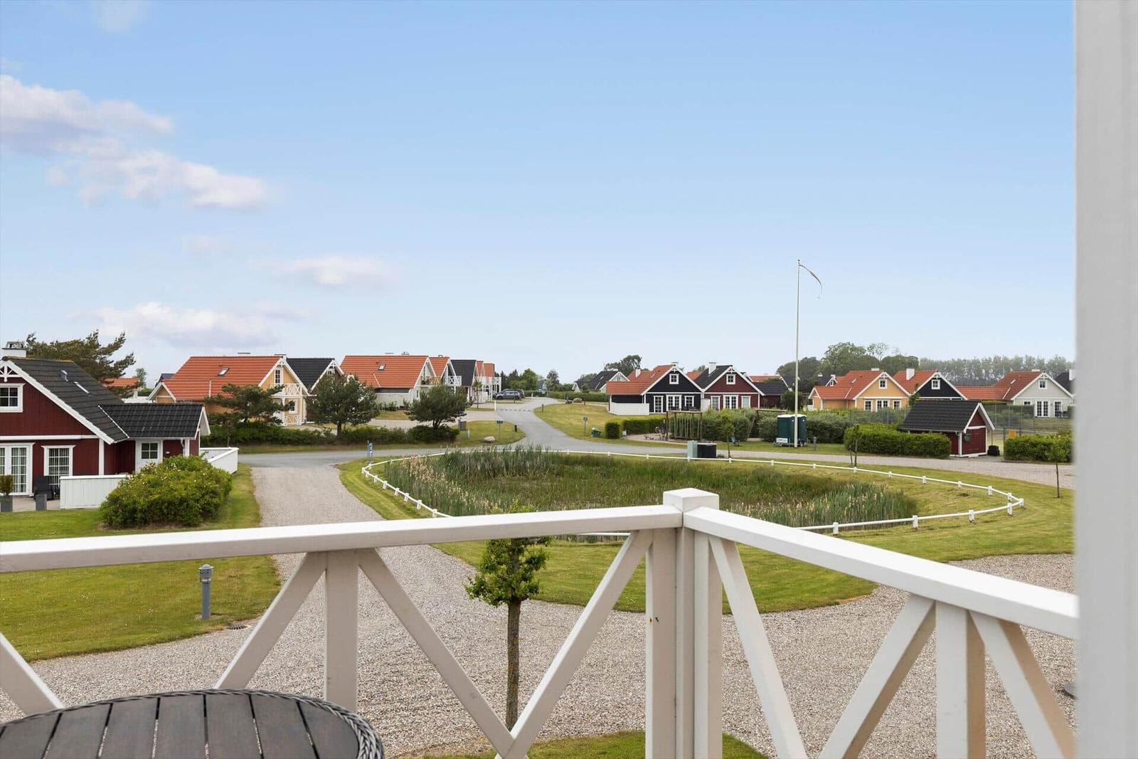 Blick von Balkon auf Ferienhausdorf mit Grünflächen und Häusern.