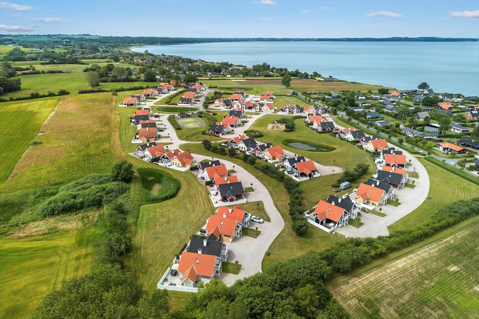 Luftbild von Ferienhäusern am See mit grünen Wiesen und Wegen.