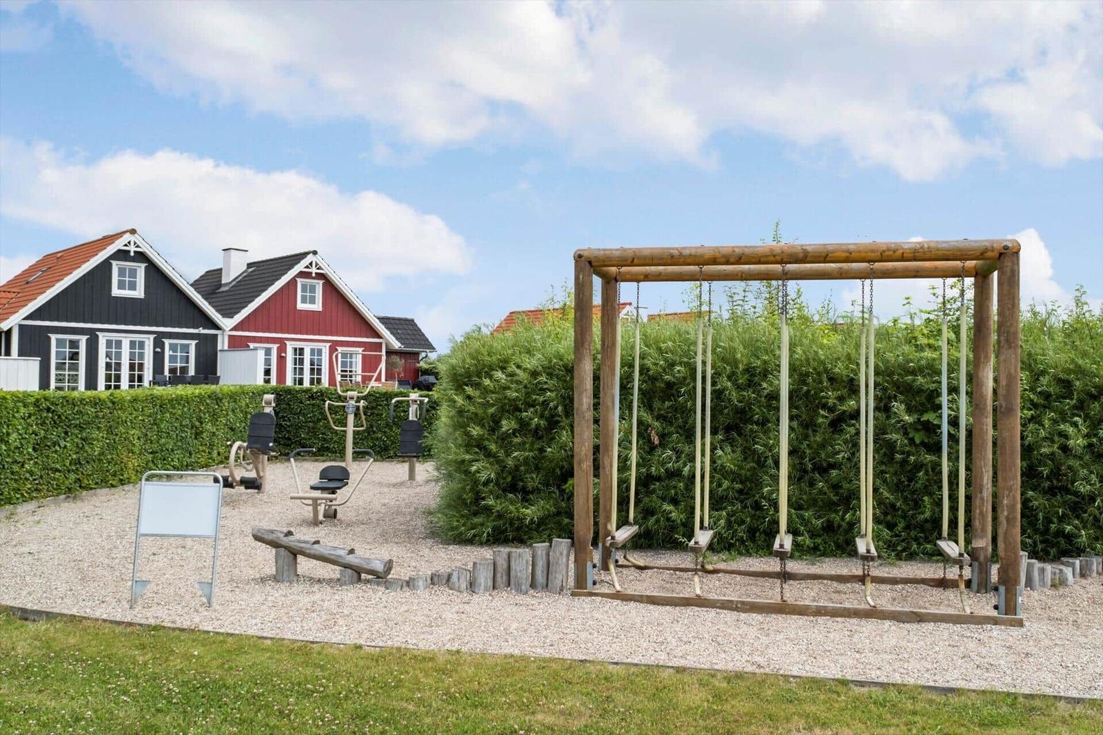Freiluftbereich mit Holzschaukel und Fitnessgeräten vor Häusern