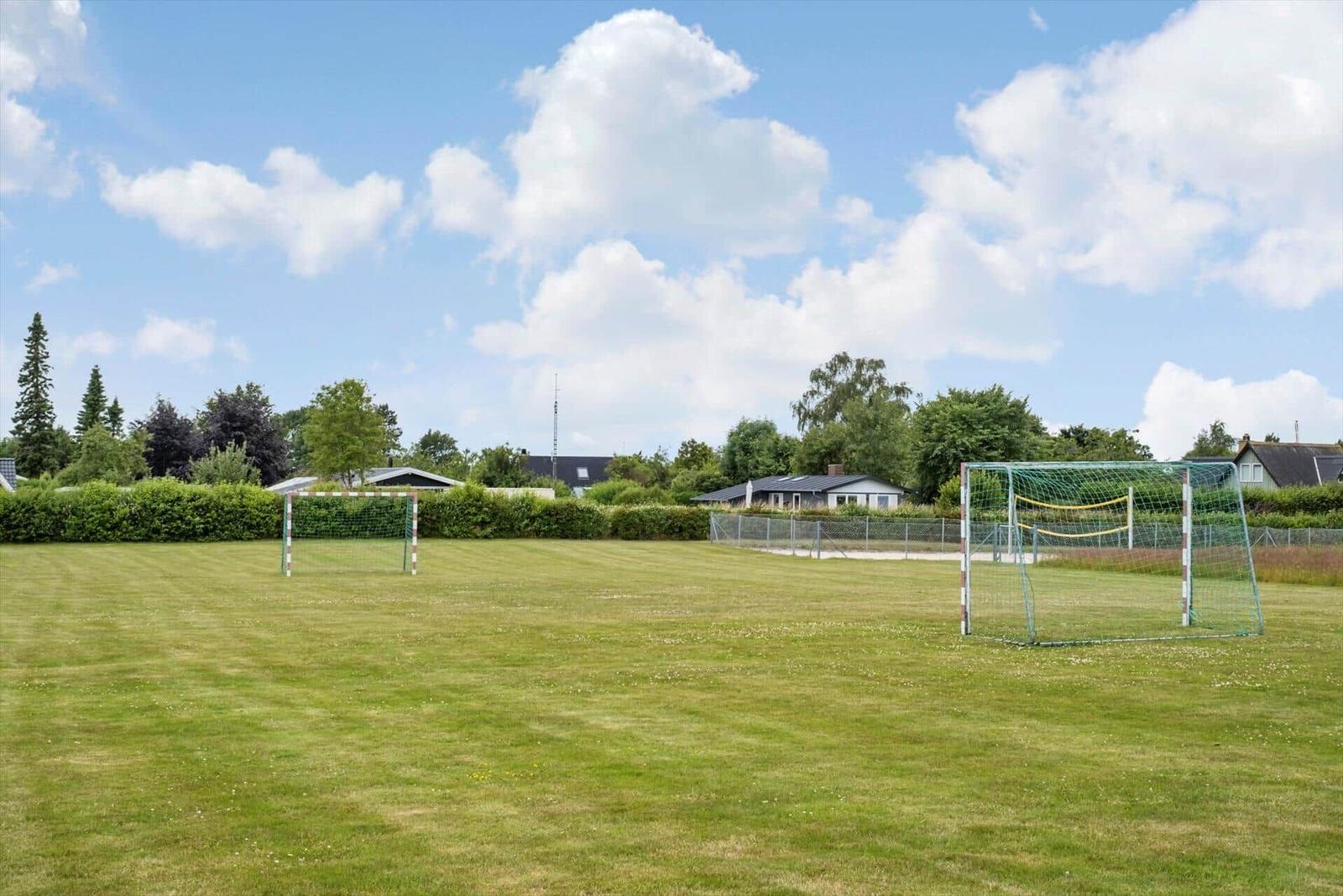 Grünes Fußballfeld mit zwei Toren unter blauem Himmel.