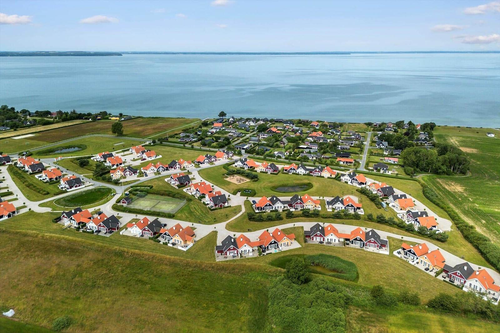 Aerial view of a coastal residential area with houses and green spaces near water.