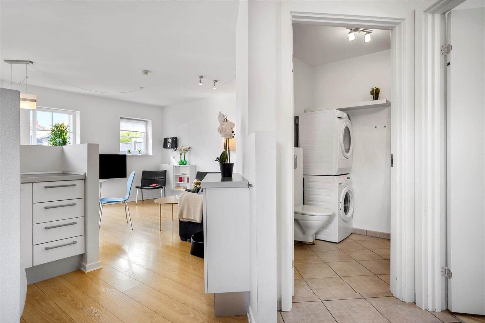 Living area with kitchenette and view into laundry room with washer and dryer.