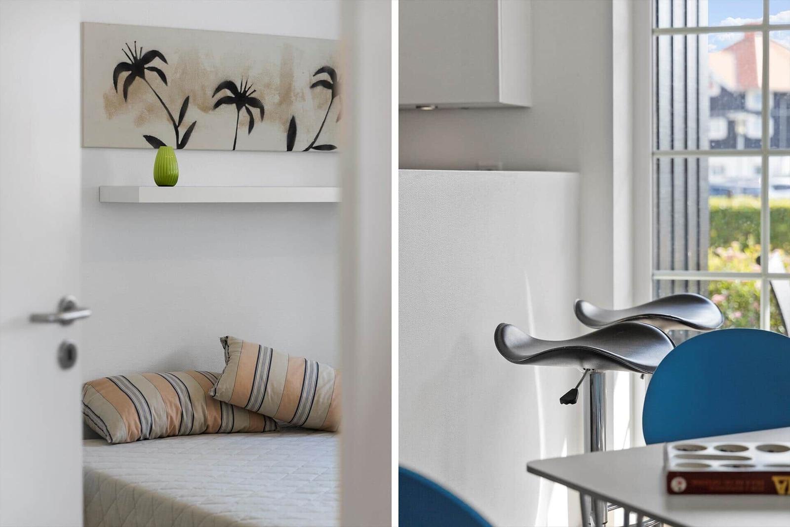 Bedroom with bed and wall art. Kitchen with bar stools and window.
