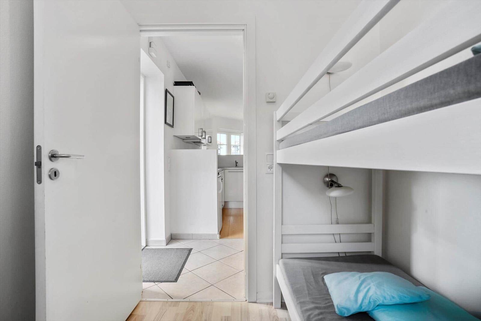 Bedroom with bunk bed and view into the kitchen.