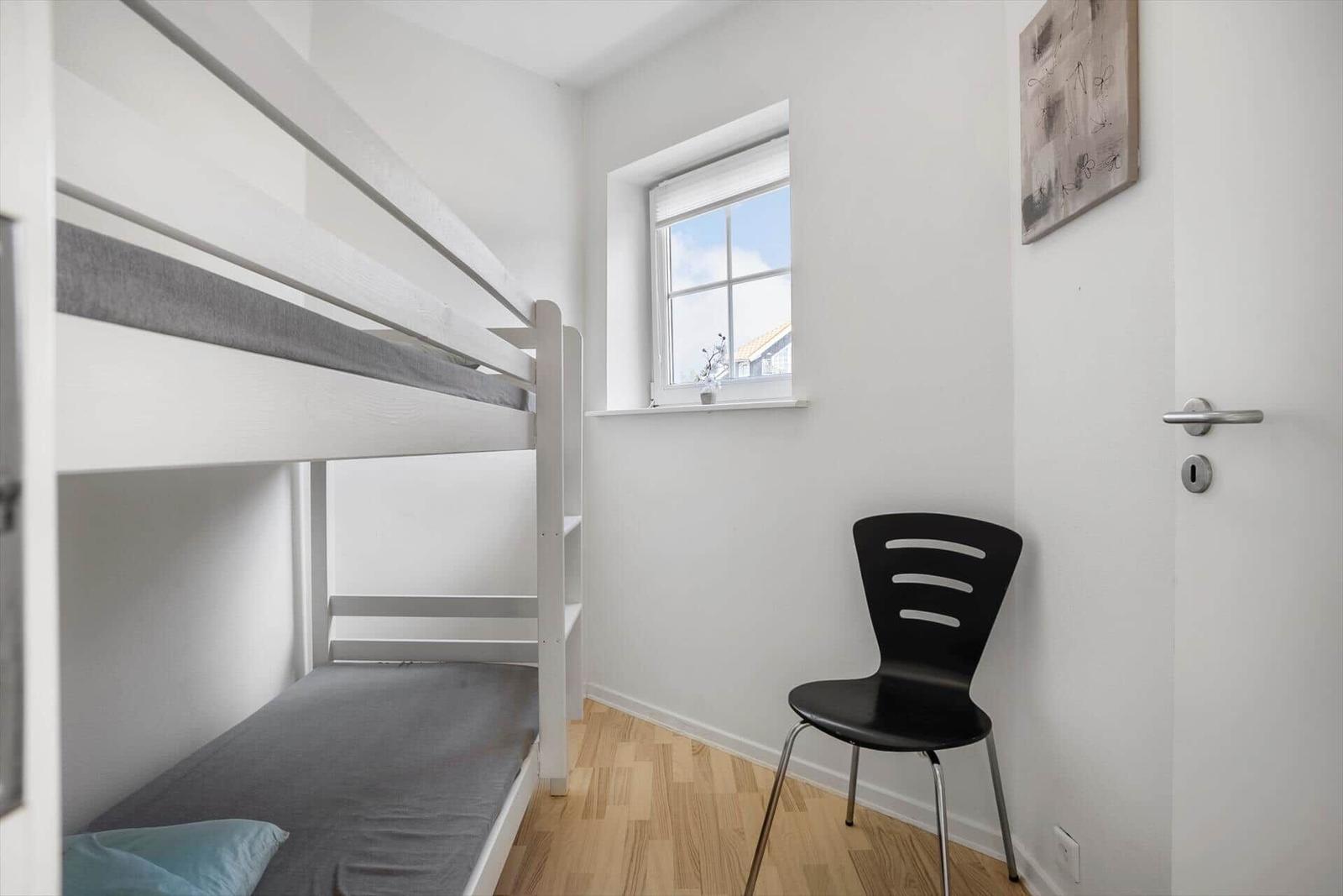 Room with bunk bed, chair, and window.
