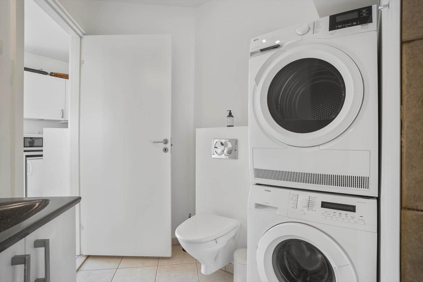 Laundry area with washer and dryer, toilet, and kitchen area visible.
