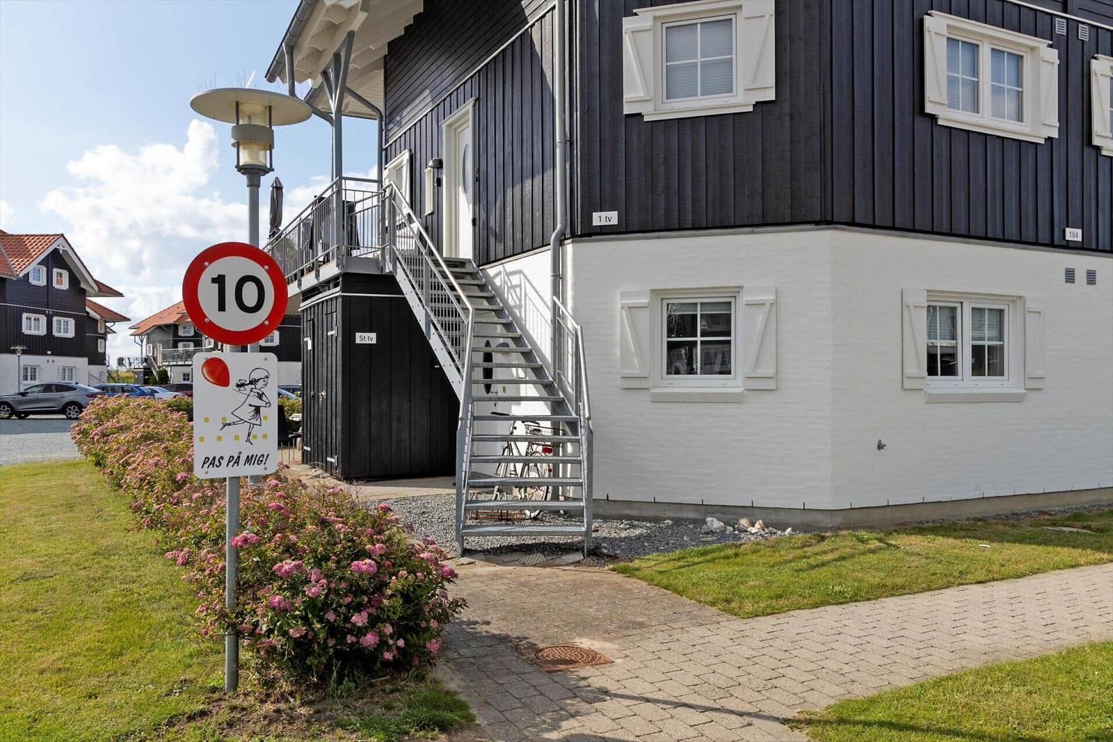 House with outdoor stairs, windows, and street sign with speed limit.