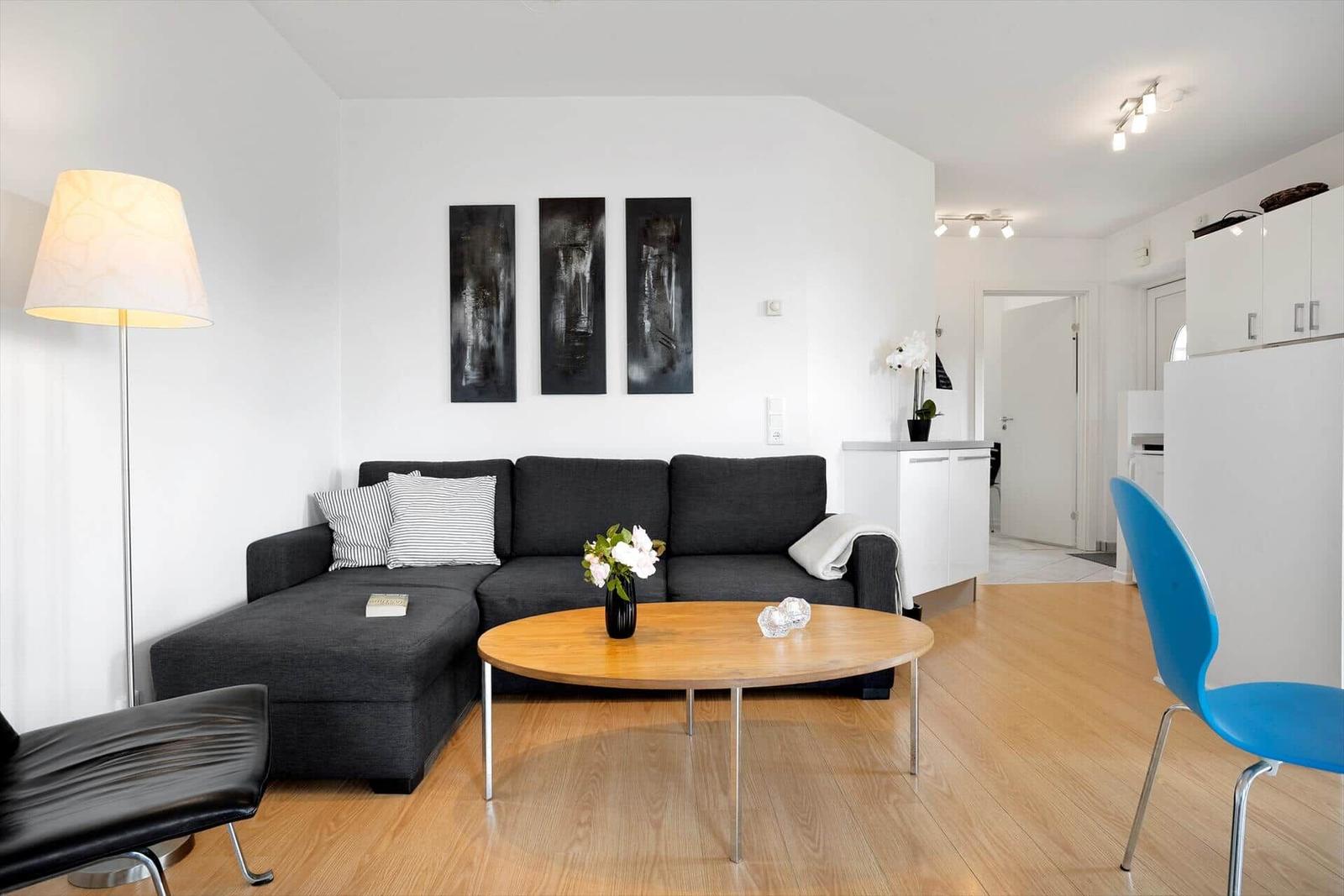 Living area with gray sofa, round table, and blue chair.