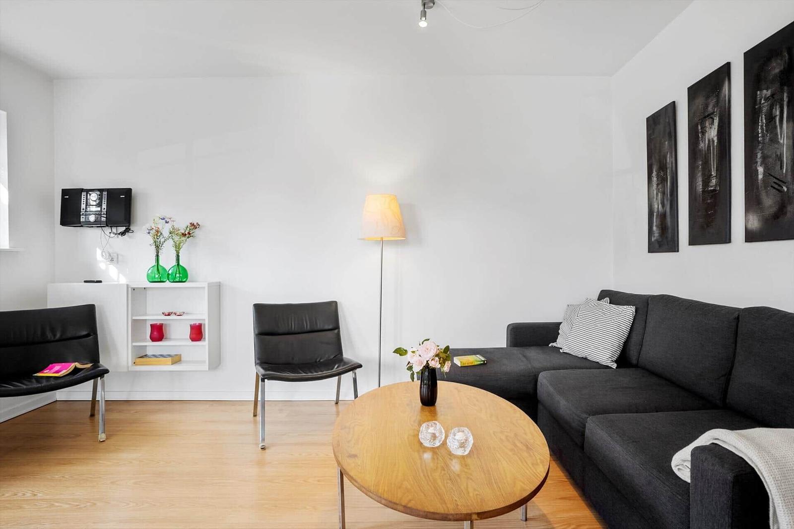 Living room with gray sofa, round table, and black chairs.
