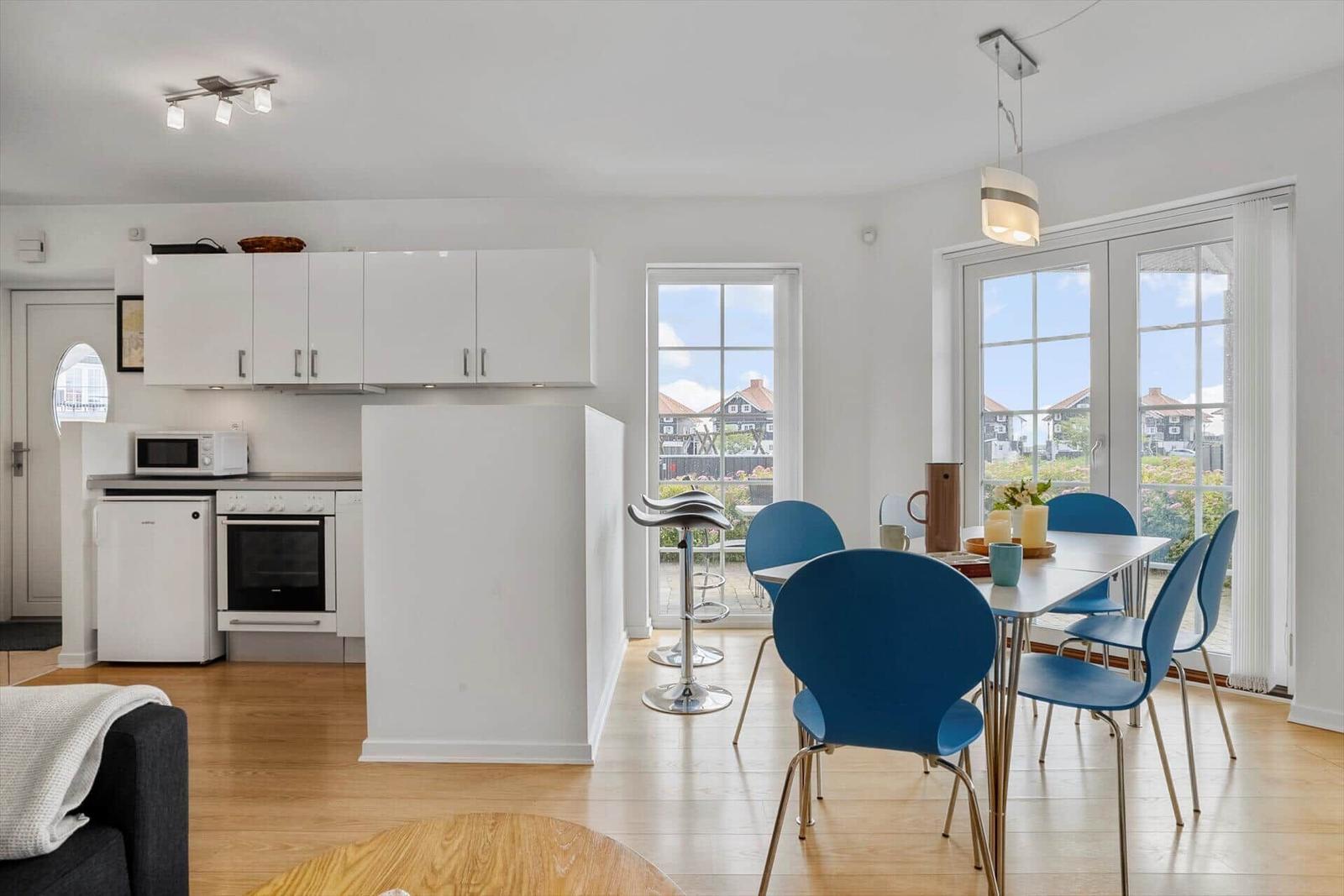 Kitchen and dining area with blue chairs and view of outdoor space.