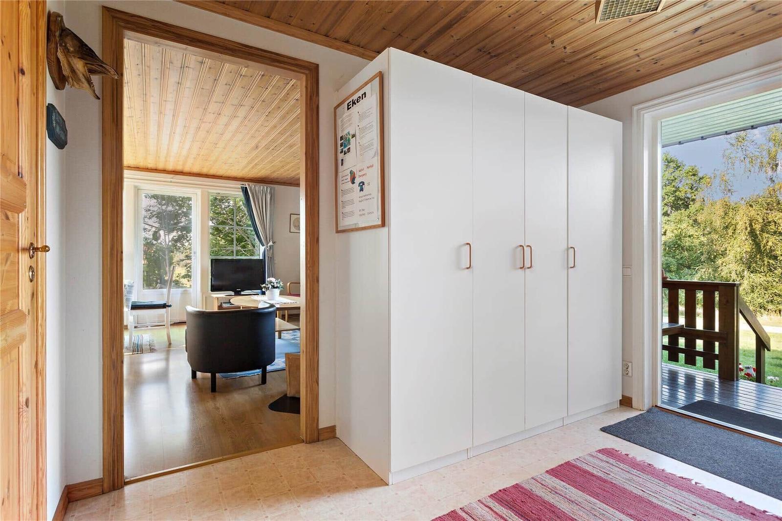 Bright entrance hall with white cabinets and wooden floor. Corridor to living room and balcony.