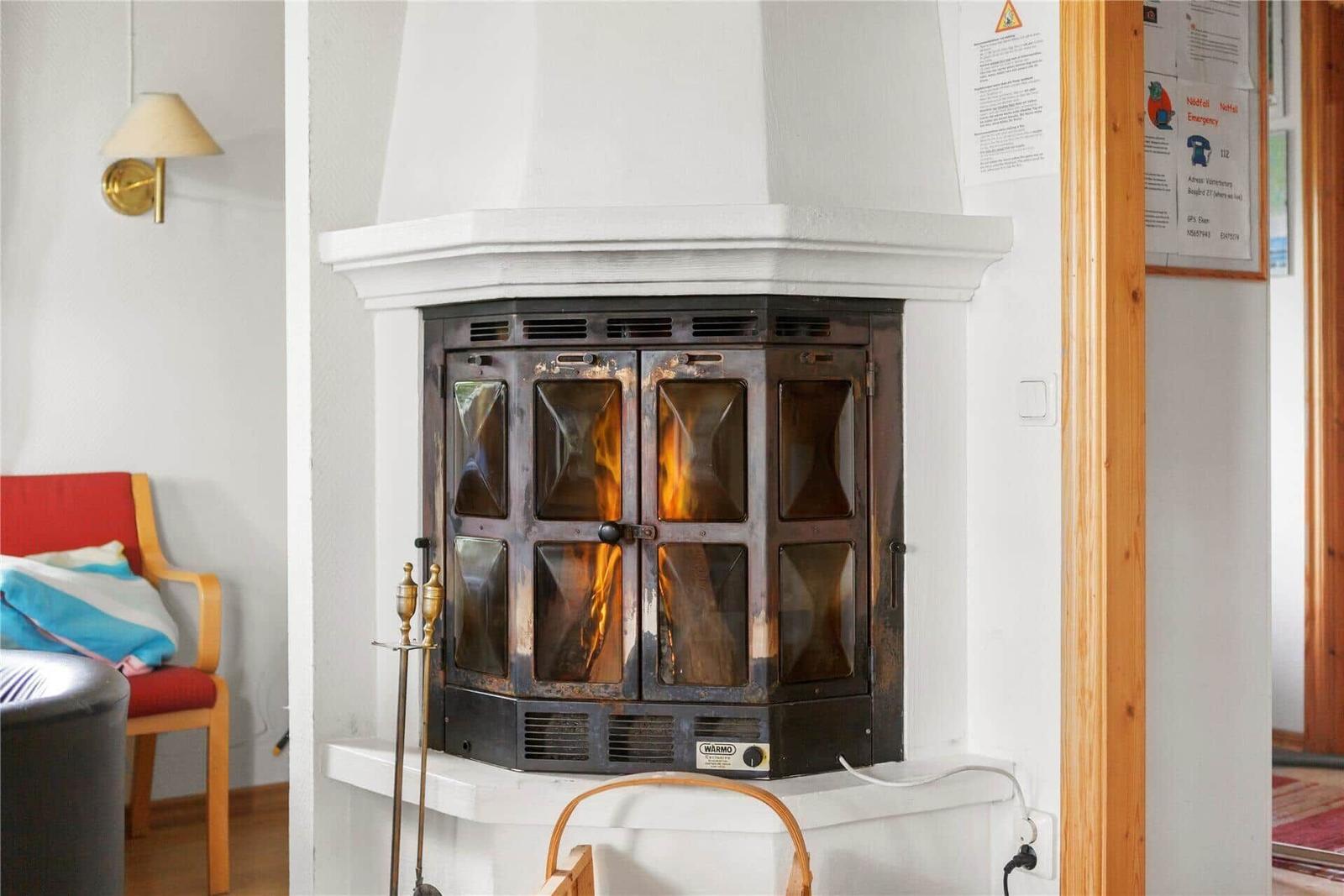 A wood-burning stove with fire in a living room with red sofa.