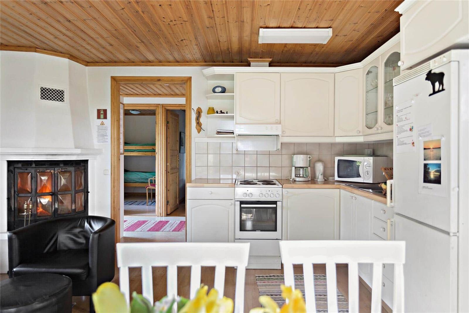Kitchen with dining area, fireplace, and view into bedroom with bunk bed.