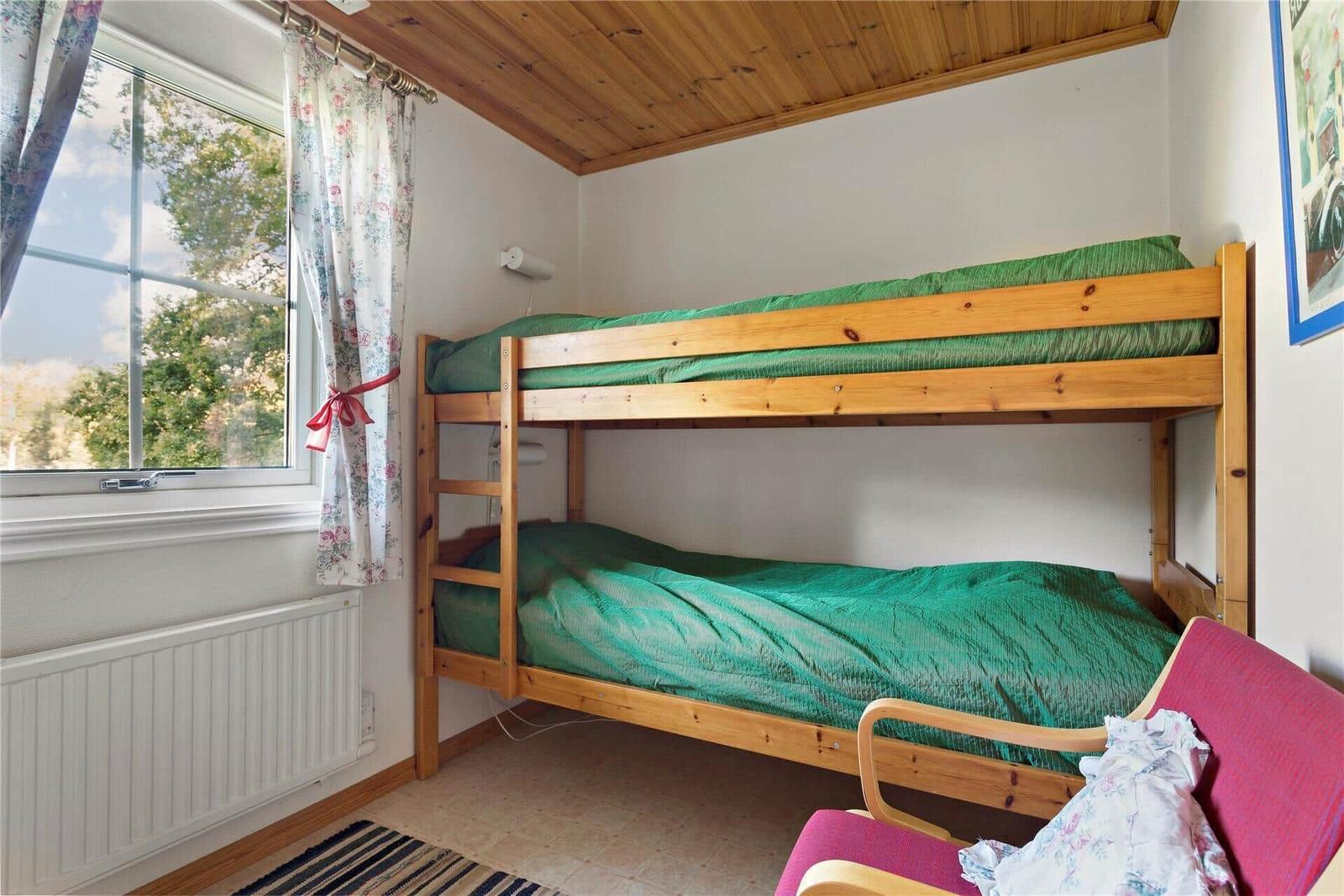 Room with bunk bed, window, and chair.