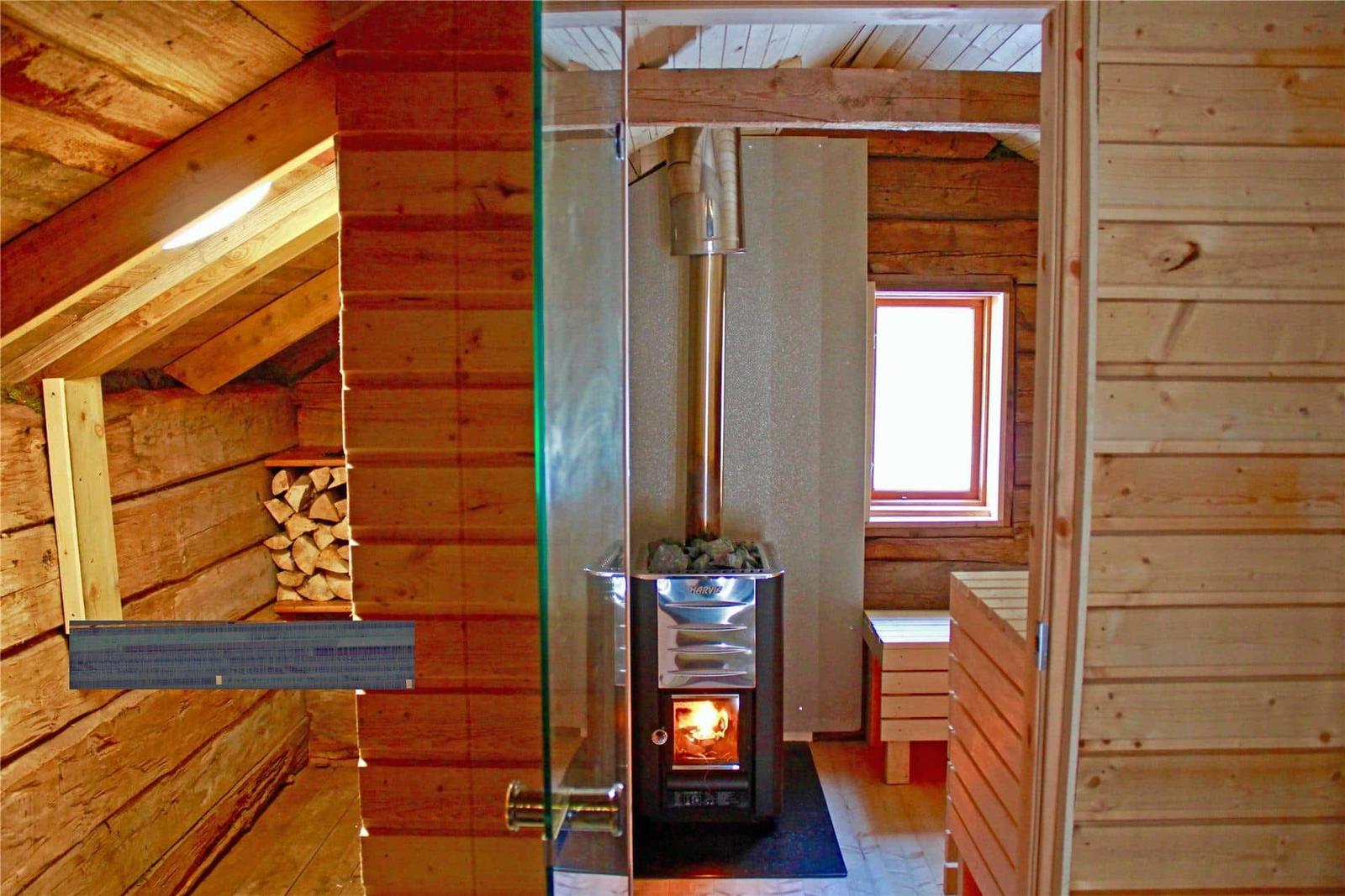 Sauna with wood stove, bench, and window. Wooden walls and roof structure visible.