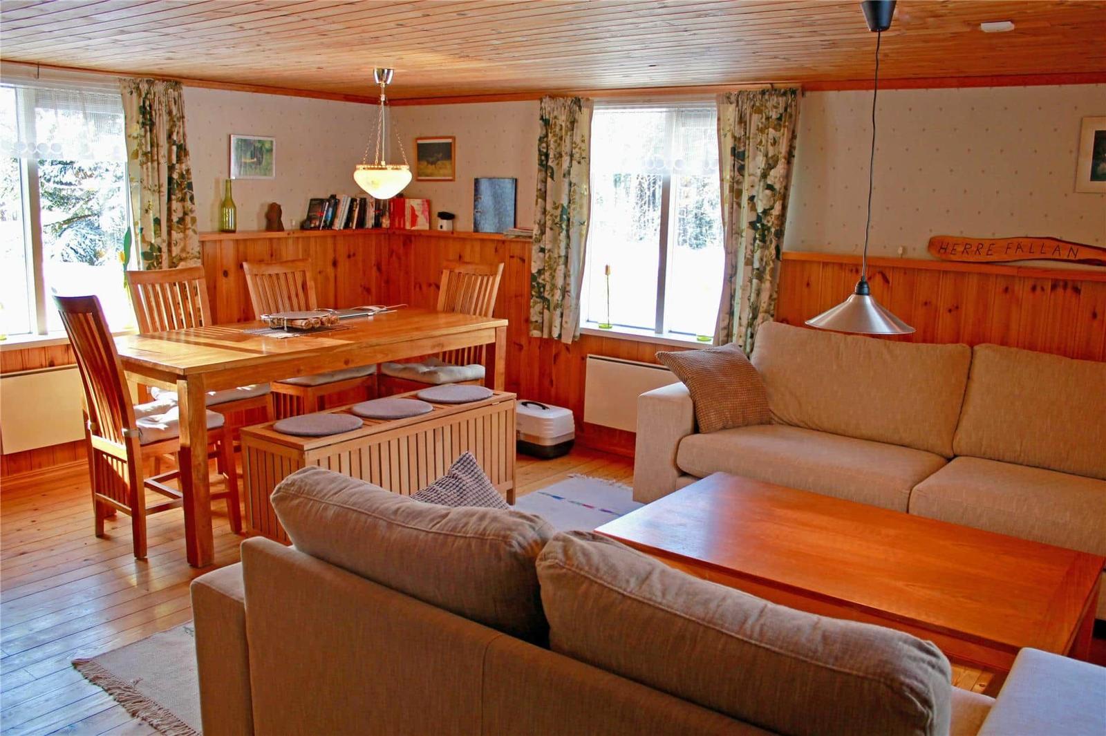 Living and dining area with wooden furniture, sofa, and view of the forest.