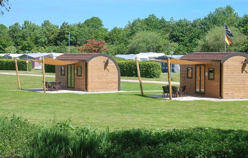 Zwei Holzhütten mit Terrassen stehen auf einer grünen Wiese.