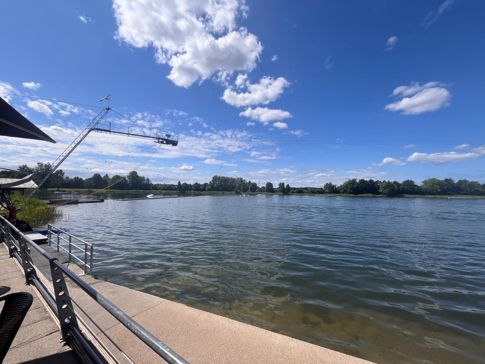 Seeufer mit Wassersportanlage und klarem Himmel.