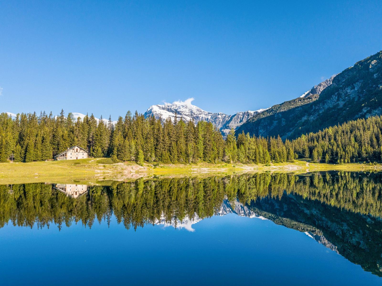 Haus am See mit Bergreflexion und Wald