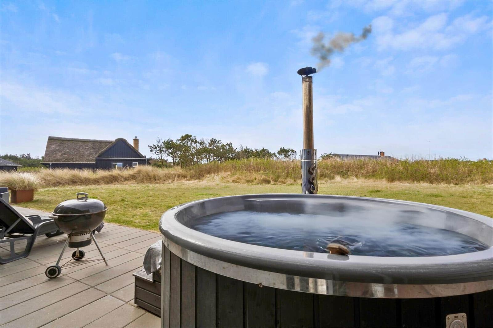 Hochwertiger Whirlpool mit Grill und Blick auf das Haus.