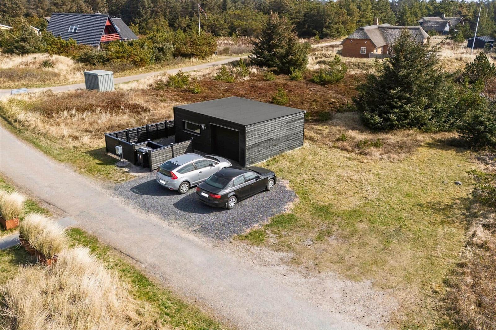 Moderne Garage mit zwei geparkten Autos in ländlicher Umgebung.