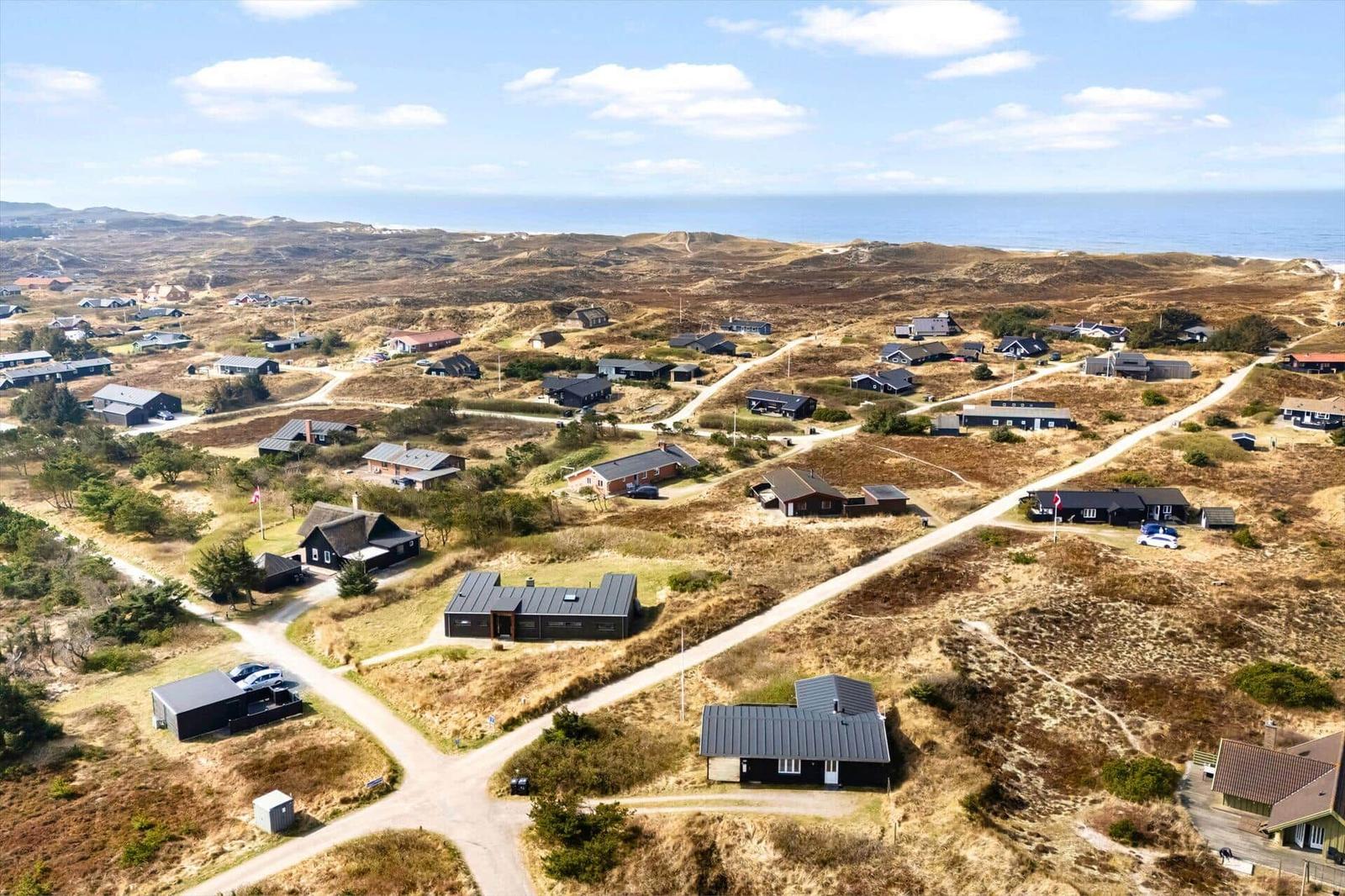 Aerial view of vacation homes on dunes near the sea.