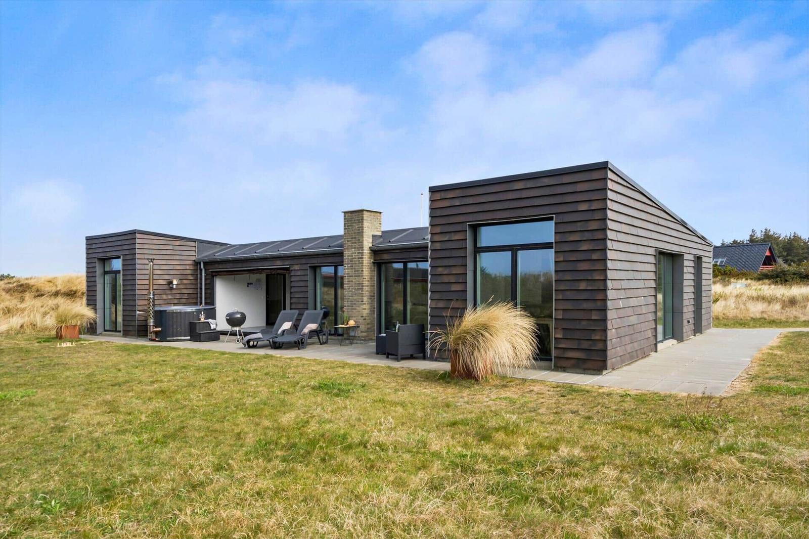 Moderne Villa mit Terrasse, Liegen und Whirlpool im Grasland.