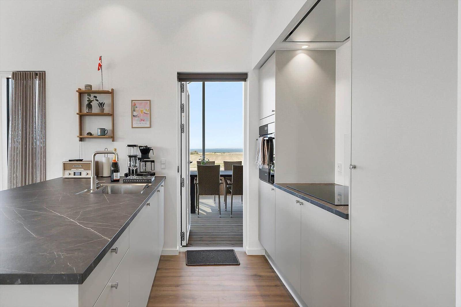 Moderne Küche mit Blick auf Terrasse und Meeresblick.