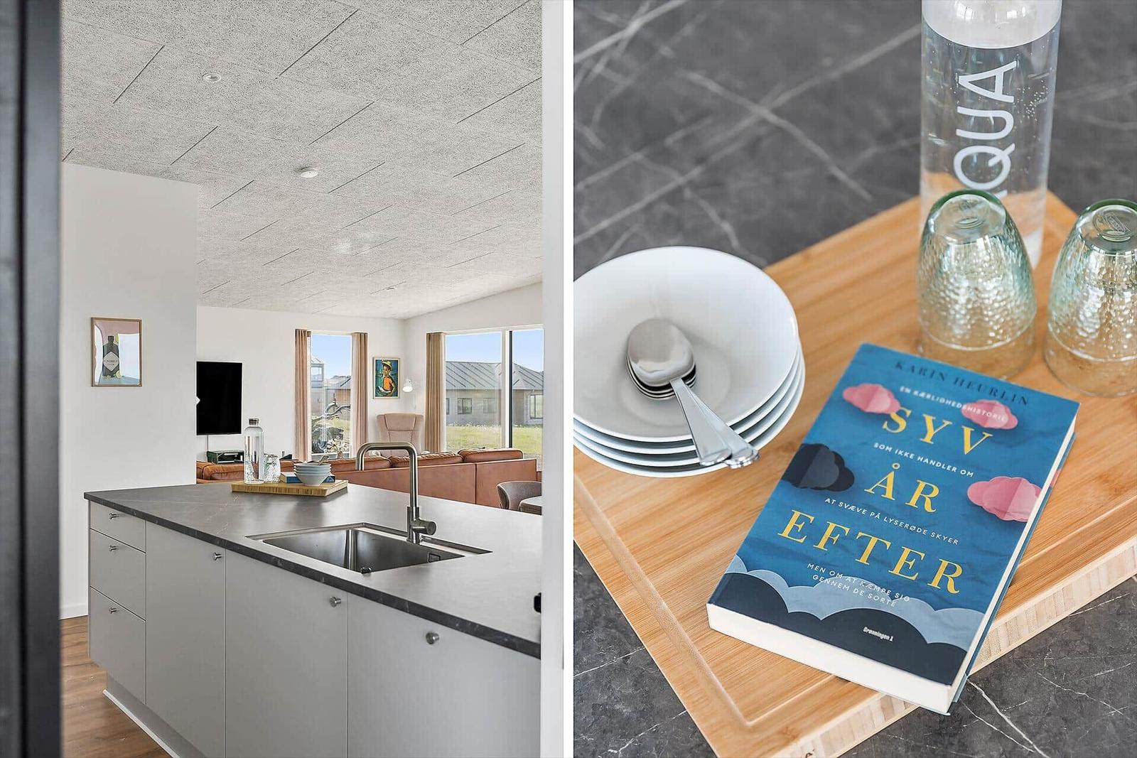 Küche mit Arbeitsplatte und Blick ins Wohnzimmer. Tisch mit Teller, Löffel, Glas und Buch.
