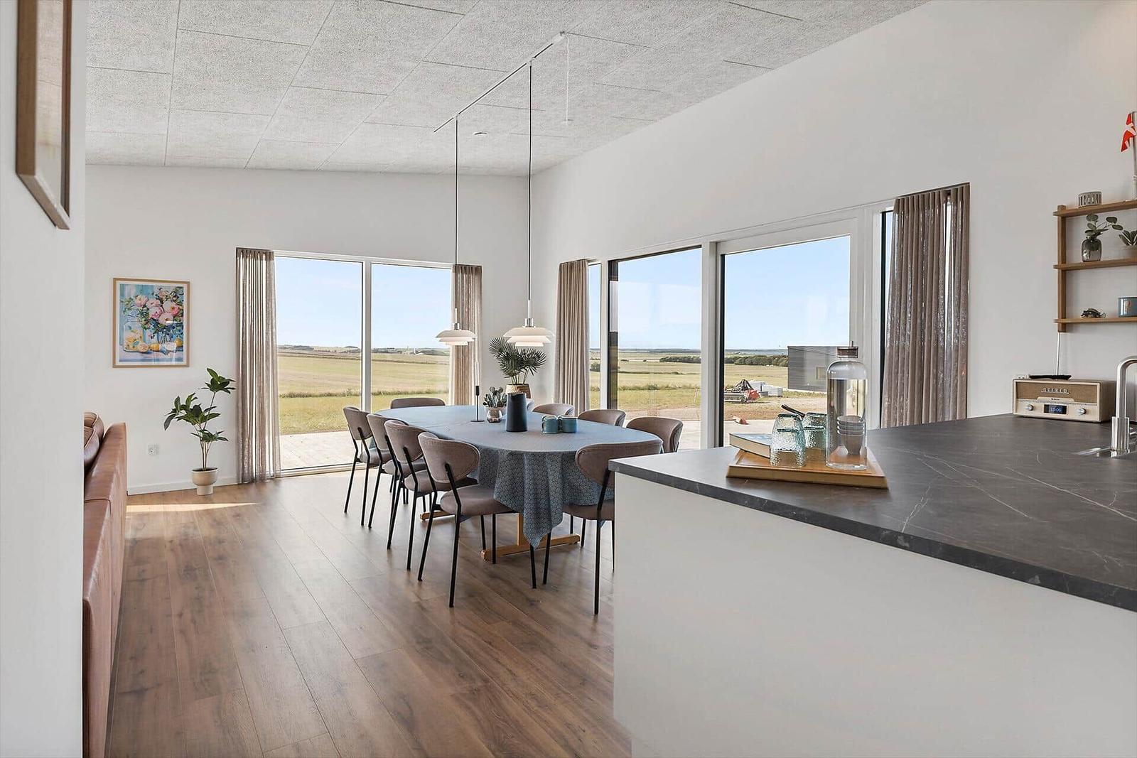 Großes Esszimmer mit Tisch, Stühlen und Blick auf Felder.