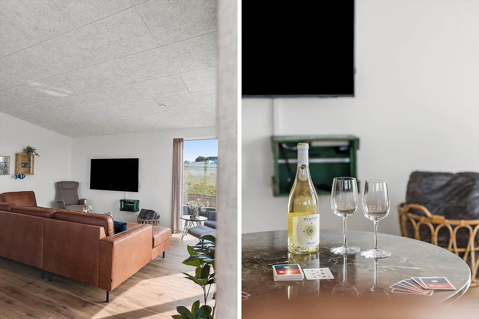 Wohnzimmer mit Sofa und Fernseher. Tisch mit Wein, Gläsern und Karten.