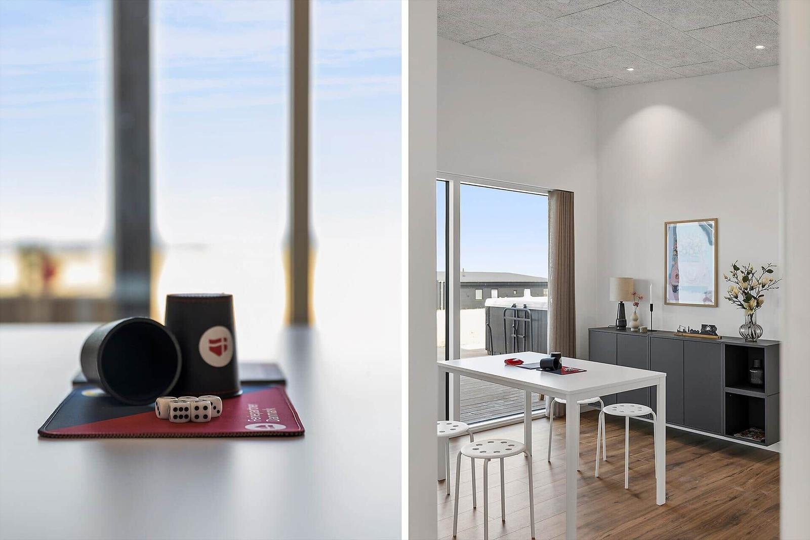 Tisch mit Würfeln und Spielzeug vor großem Fenster. Essbereich mit Tisch, Stühlen und Schrank.