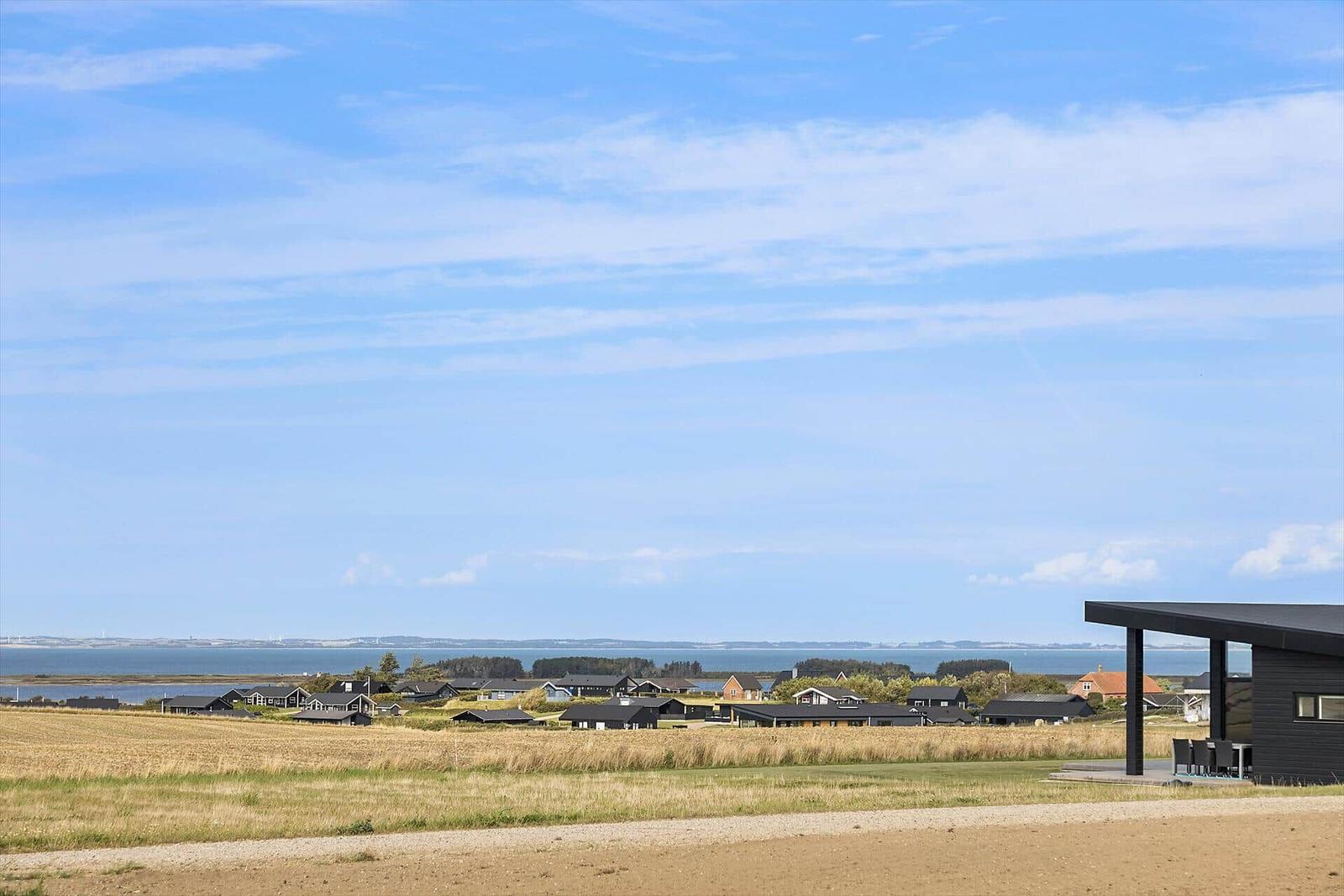 Schwarze Hütten mit Blick auf das Meer und Felder.