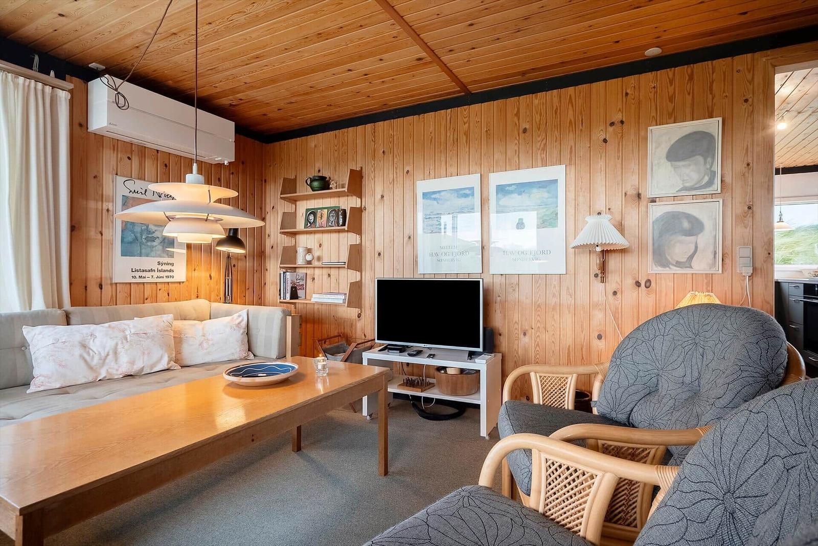 Wohnzimmer mit Holzwand, Sofa, Couchtisch und Fernseher.