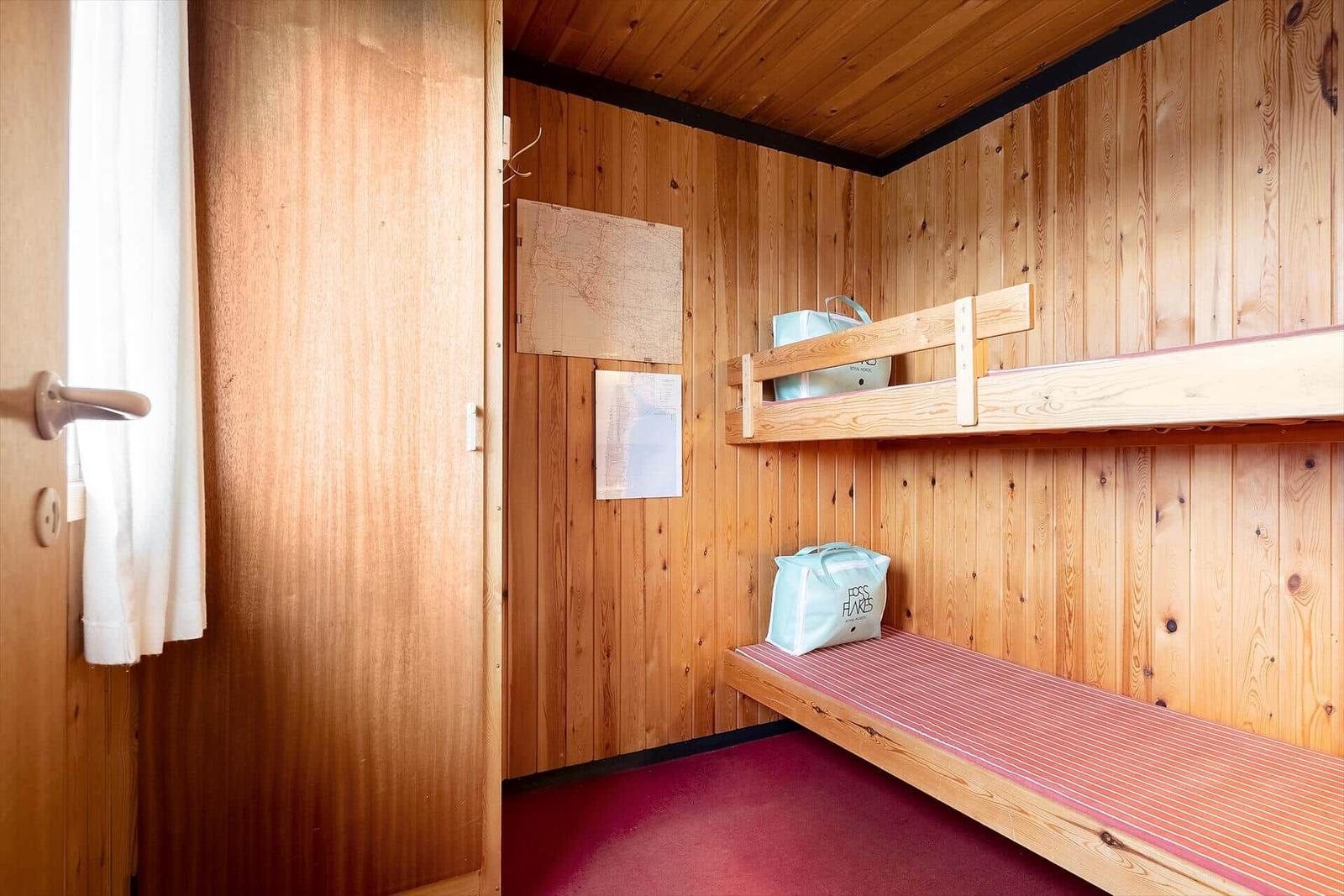 Kabine mit Holzwand, Schlafcouch und Karte an der Wand.