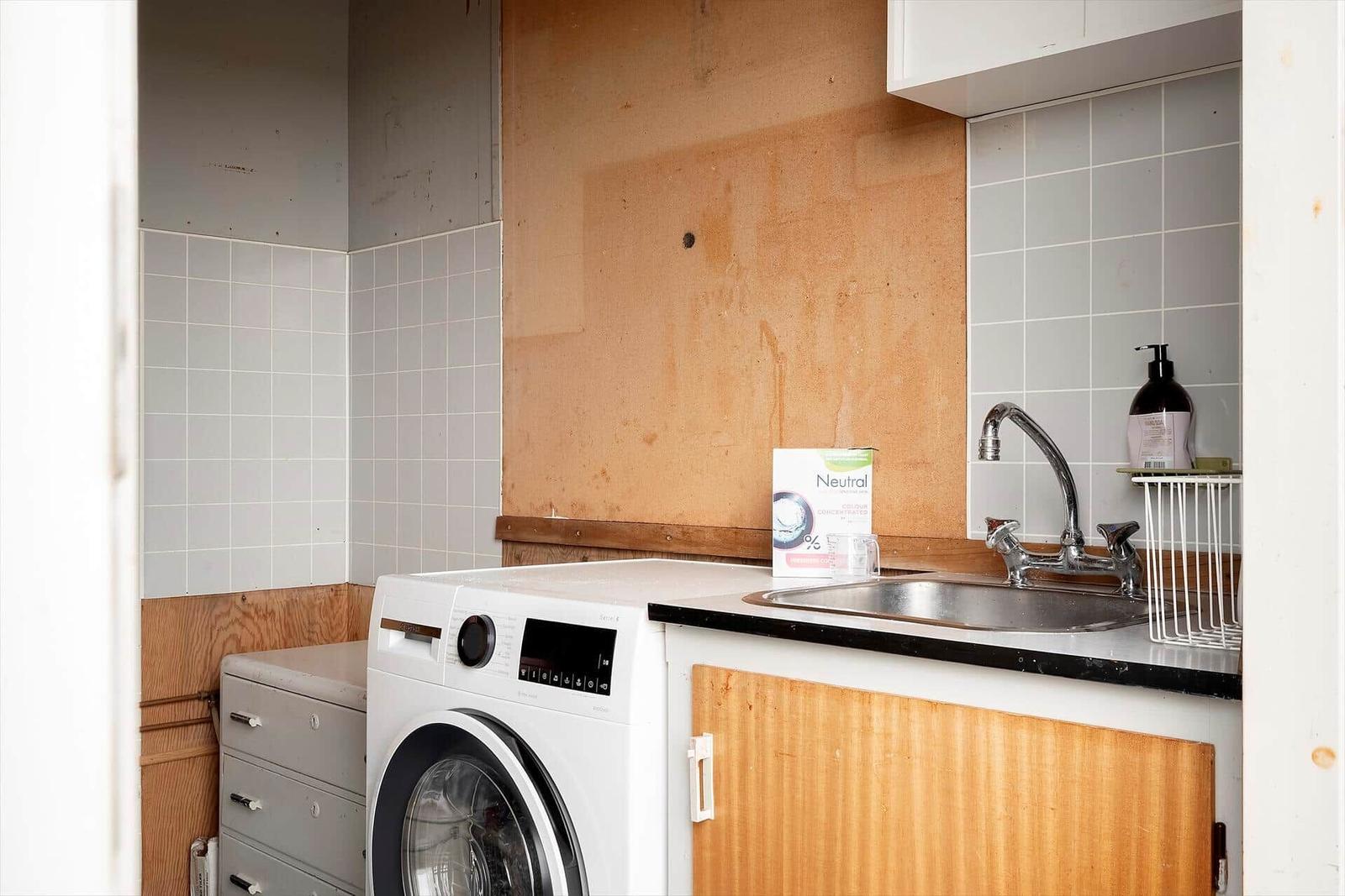 Waschmaschine neben Spüle mit Wasserhahn und Seife