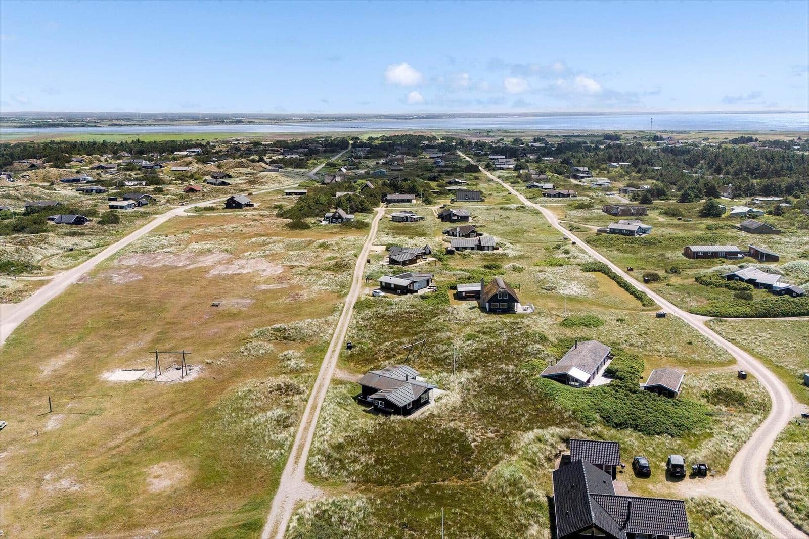 Aerial view of a coastal village with scattered houses and sandy paths.