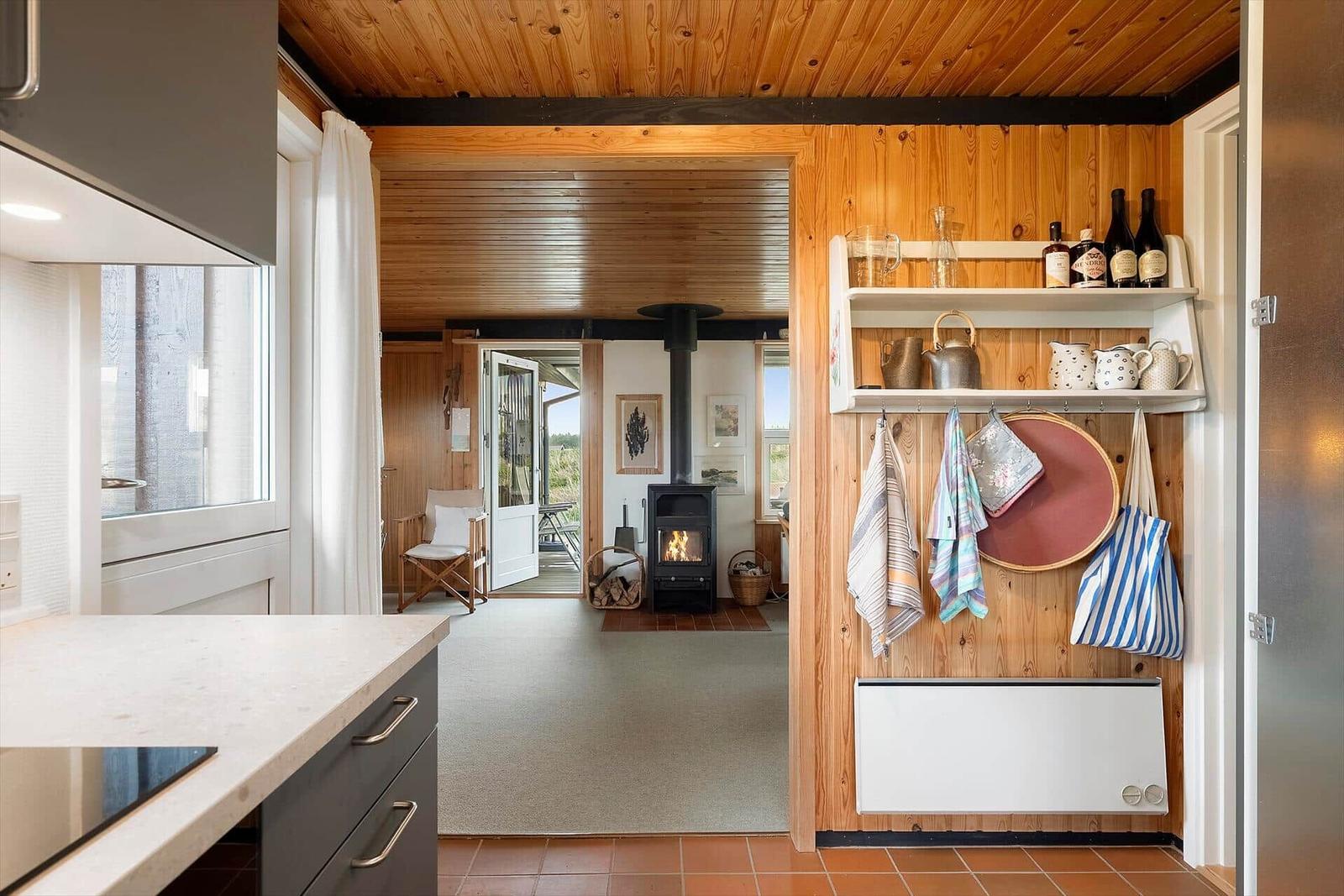 Küche mit Blick auf Wohnbereich mit Kamin und Holzwand
