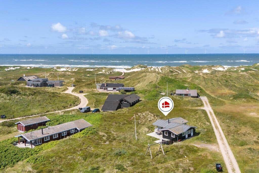 Haus auf Dünen mit Blick auf das Meer und Windkraftanlagen