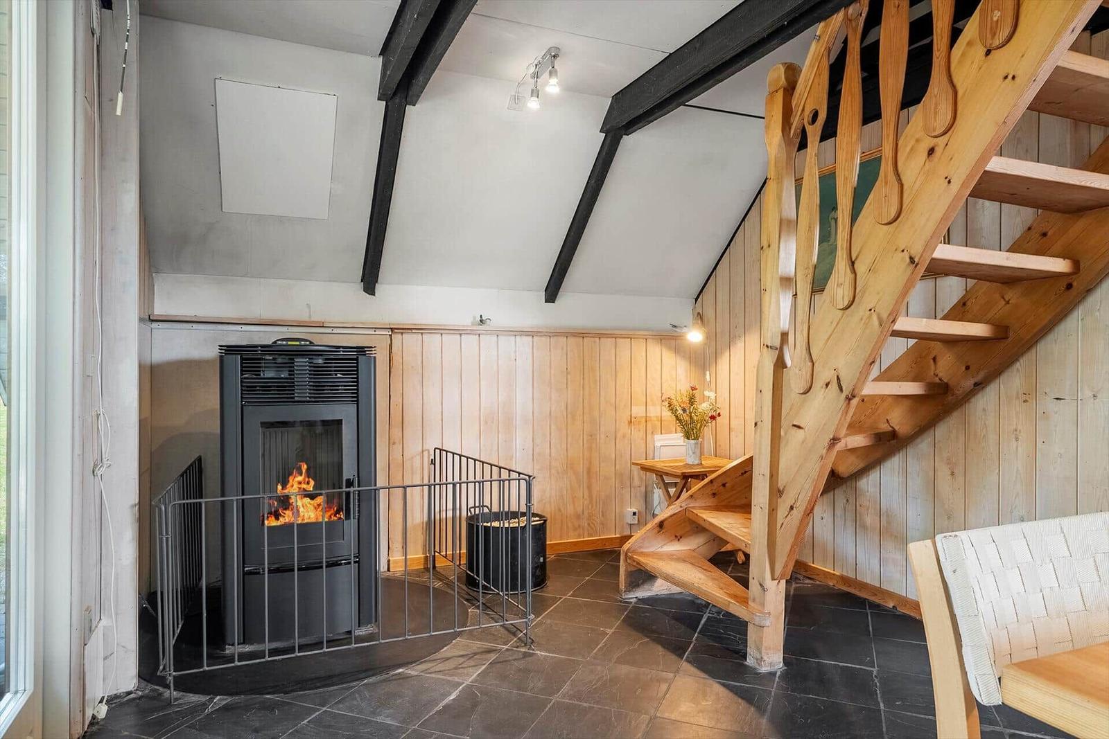 Room with fireplace, wooden staircase, and dark floor