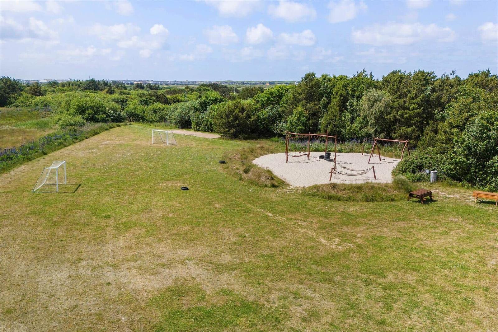 Large green yard with playground, soccer goal, and benches.