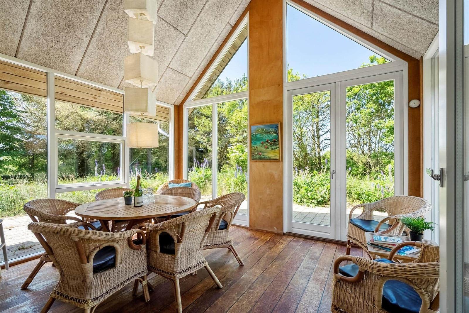 Seating area with dining table and chairs, large windows and doors to garden