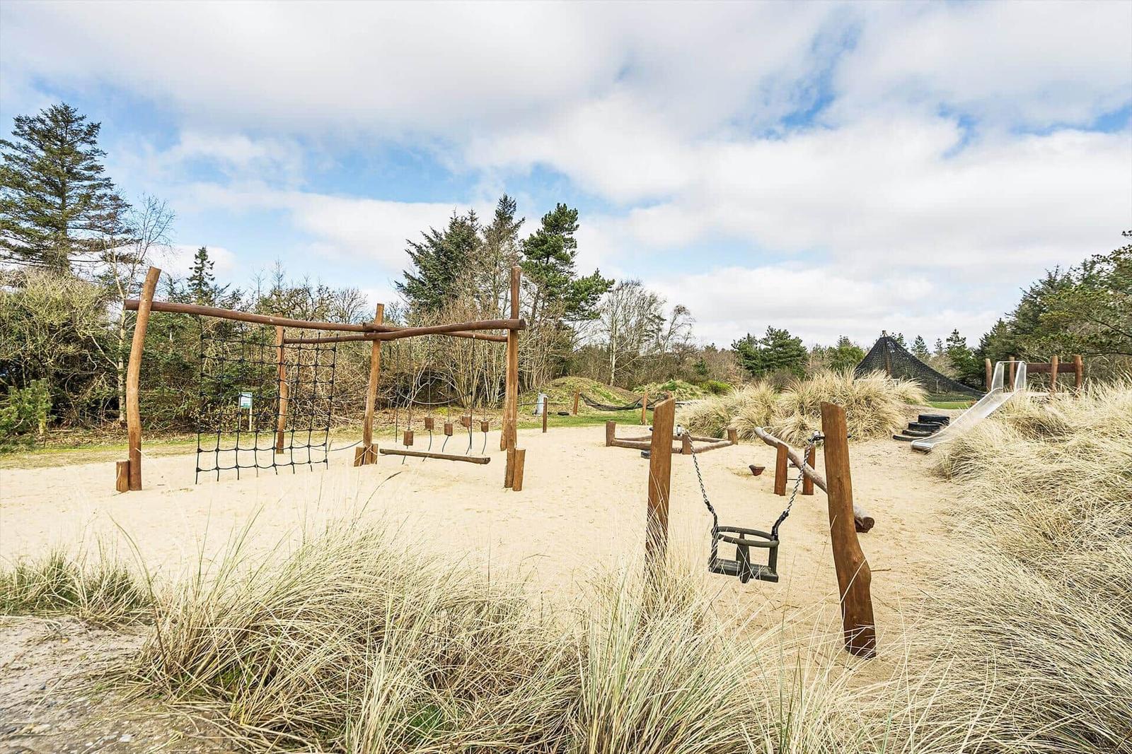 Outdoor play area with climbing frame and swing on sand