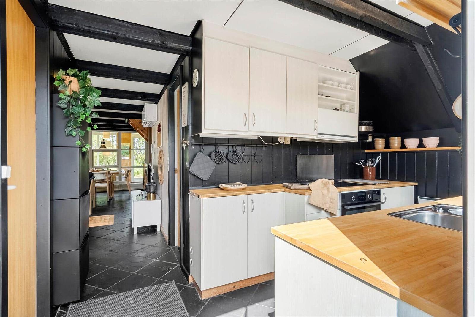 Kitchen with wooden surfaces and black walls. View into the dining room.