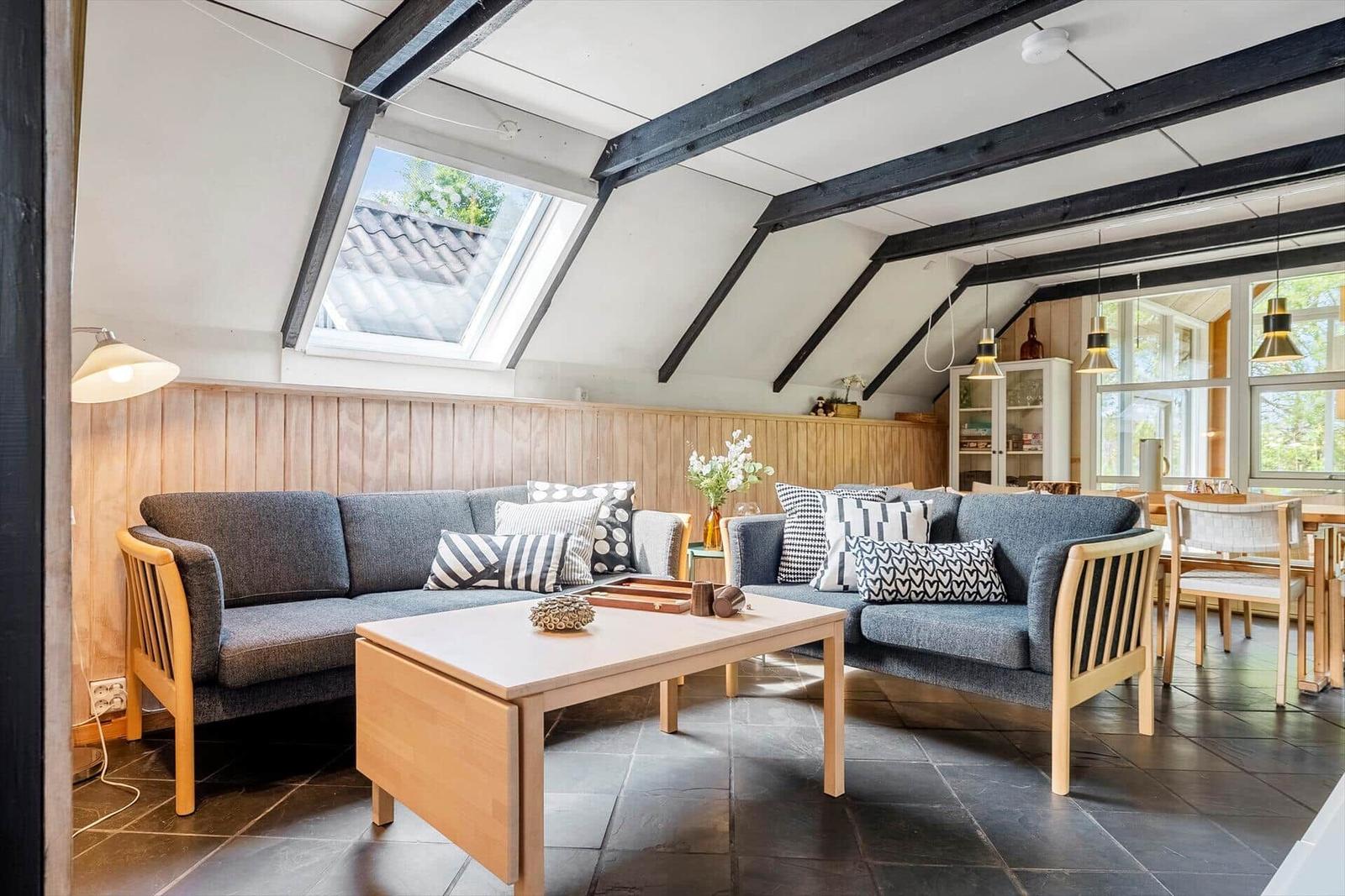 Living area with gray sofa, wooden table, and skylight.