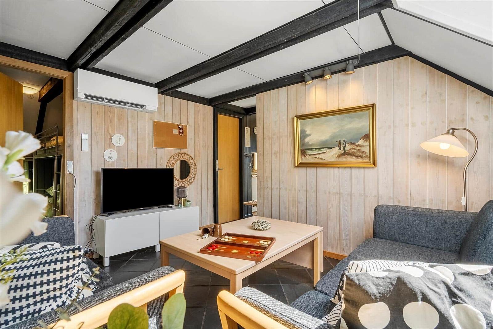 Living room with sofa, coffee table, and TV against wood wall