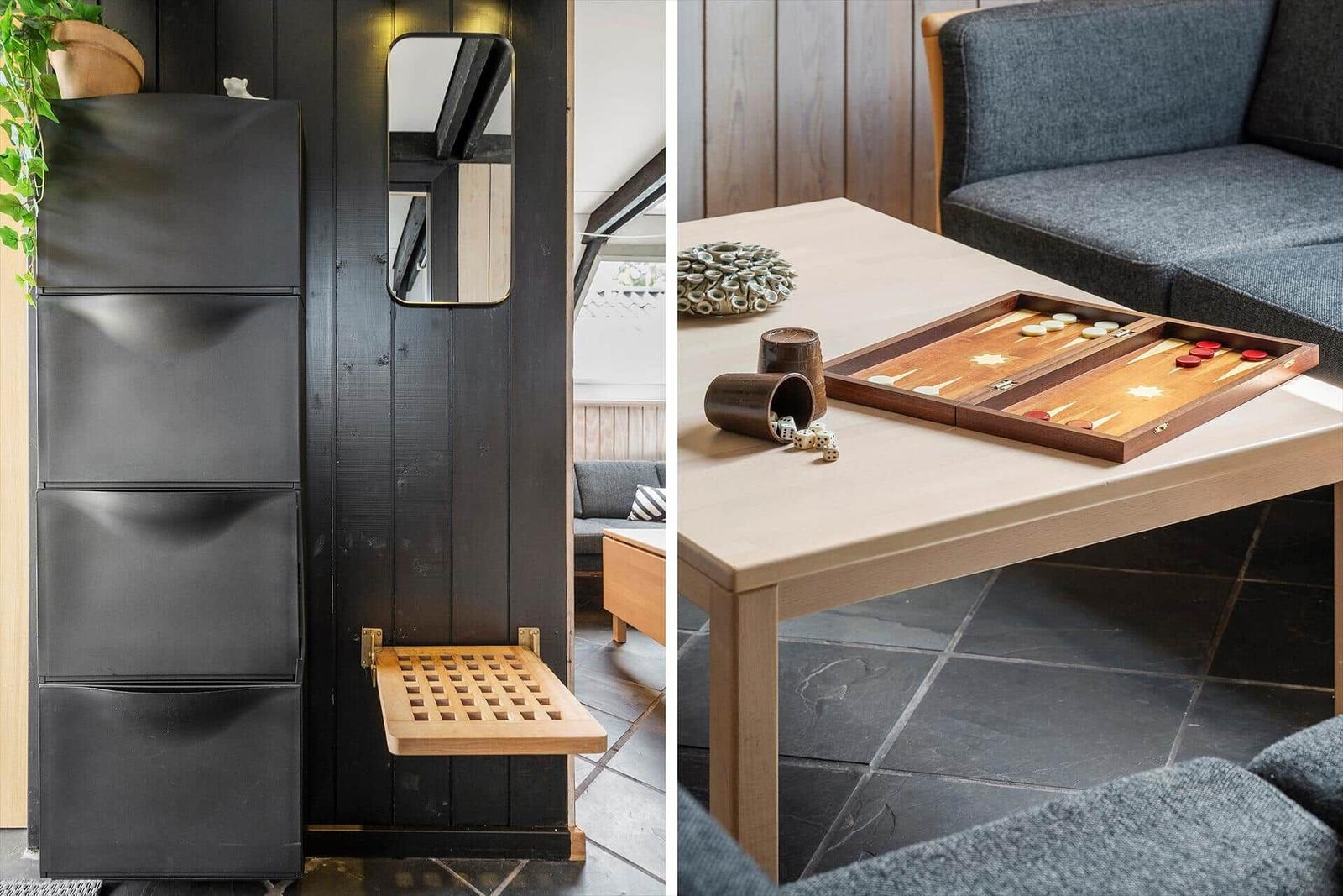 Black cabinet with mirror and wooden stool. Table with backgammon and sofa.