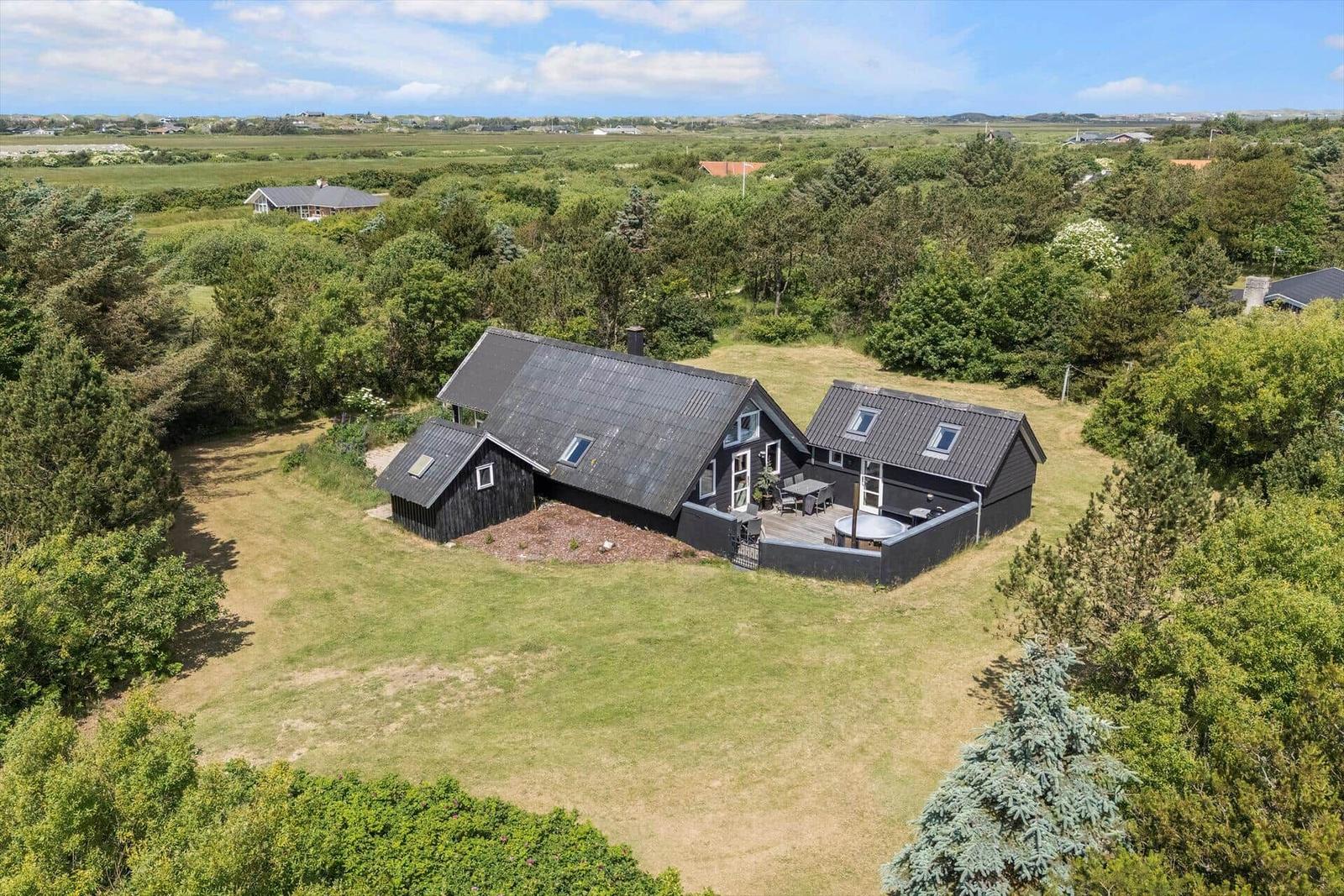 Black house with terrace and grill area in green surroundings