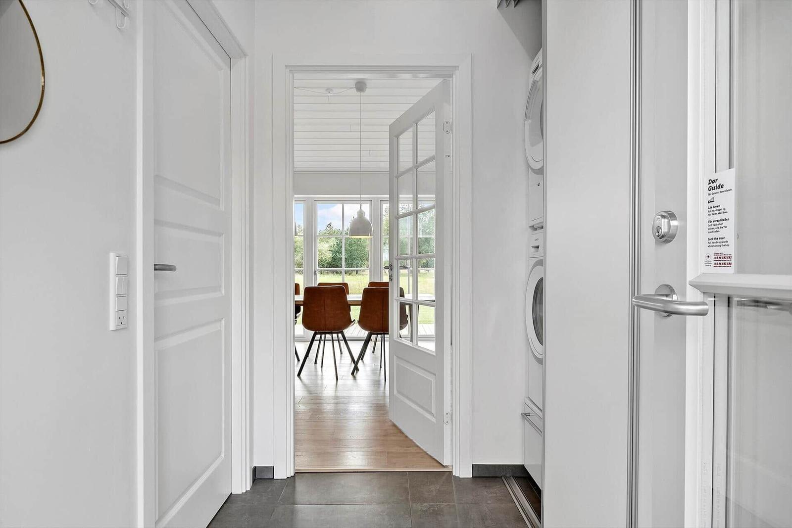 Flur mit Waschmaschine, Tür zum Esszimmer mit Tisch und Stühlen.
